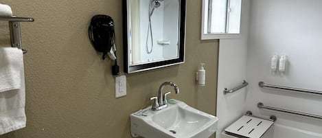 A bathroom with a white sink, a mirror, a shower, and a towel rack.