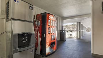 Um corredor com uma máquina de Coca-Cola e um refrigerador à esquerda.