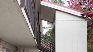 A building with a brick facade, a covered walkway, and a staircase leading to an upper level. - Cocomo Inn and Suites (Moultrie)