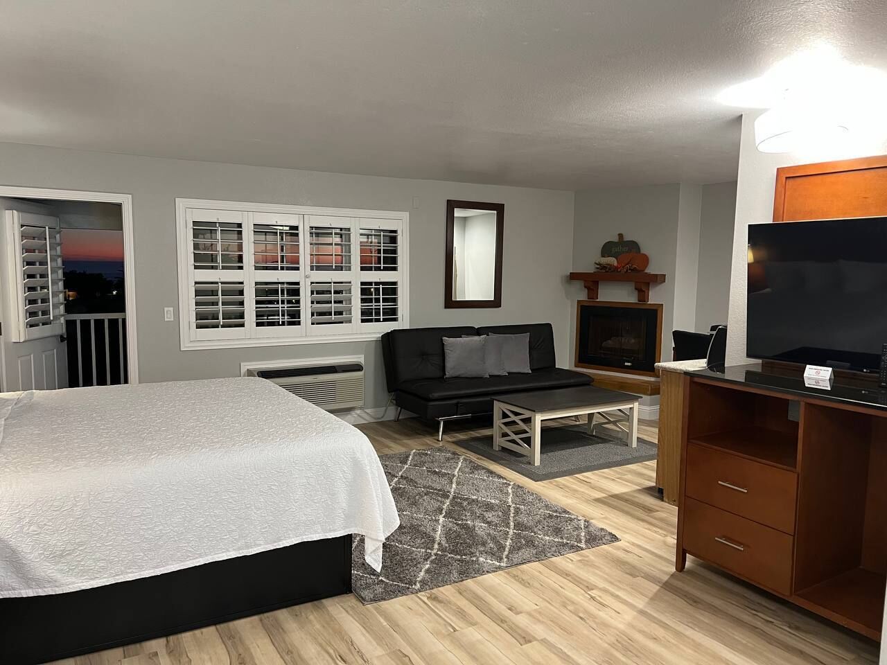 Un dormitorio con cama, sofá, televisor y escritorio.