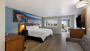 A hotel room with a bed, a desk, a chair, a sofa, a TV, a painting, and a window with a view. - Comfort Inn near Hearst Castle - Cambria (San Simeon)