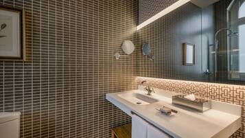 Un baño moderno con un espejo grande, un lavamanos blanco y un salpicadero de azulejos estampados.