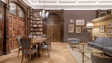 A traditional library with wooden bookshelves, a large wooden door, and a chandelier.