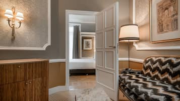 Une chambre d’hôtel avec un lit, un canapé, une armoire en bois, une lampe et un tableau encadré au mur.