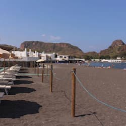 Praia particular, areia preta, espreguiçadeiras, guarda-sóis