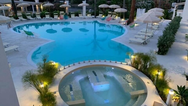 A swimming pool with a hot tub in the center, surrounded by lounge chairs and umbrellas. - Les Sables Noirs & Spa (Lipari)