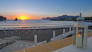 A beach with a sunset, a wooden deck, and a lantern. - Les Sables Noirs & Spa (Lipari)