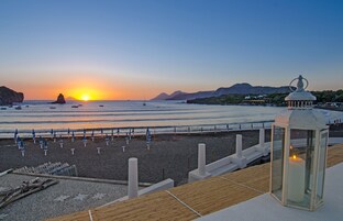 Playa privada, arena negra, sillas reclinables de playa, sombrillas