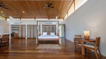 Un dormitorio amplio con techo de madera, una cama con dosel, una mesa de comedor con sillas y un ventilador de techo.