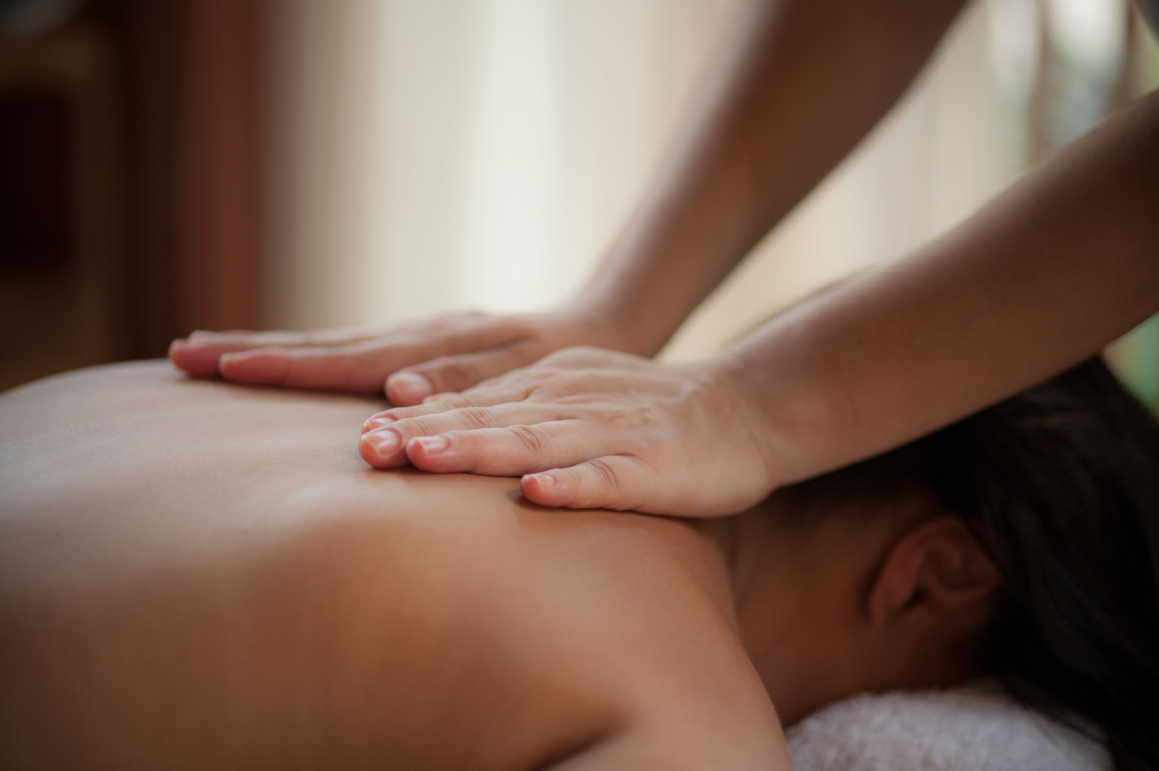 Gros plan sur des mains effectuant un massage sur le dos d’une personne.