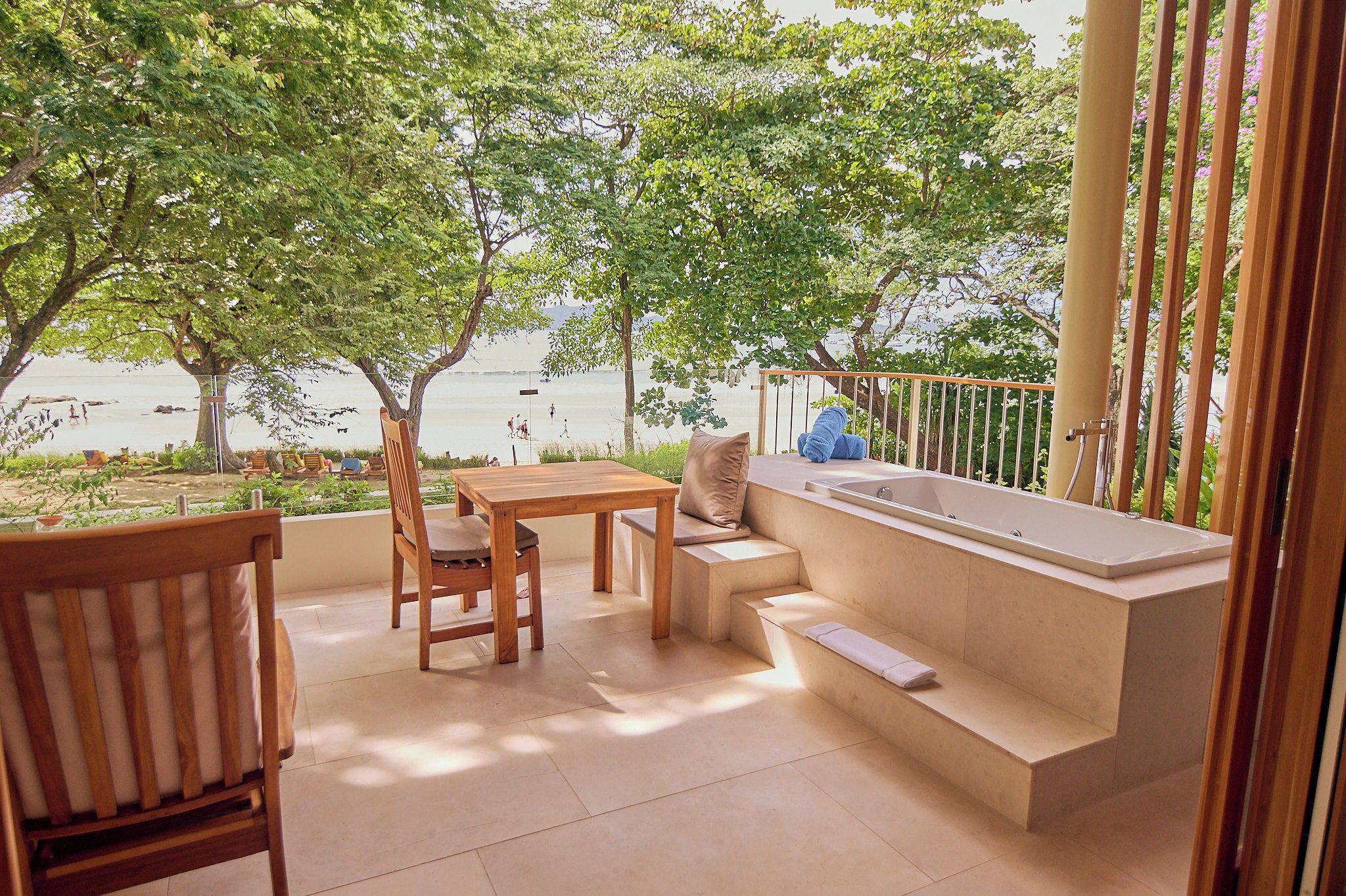 A balcony with a wooden table and chairs, a built-in bench, and a bathtub.