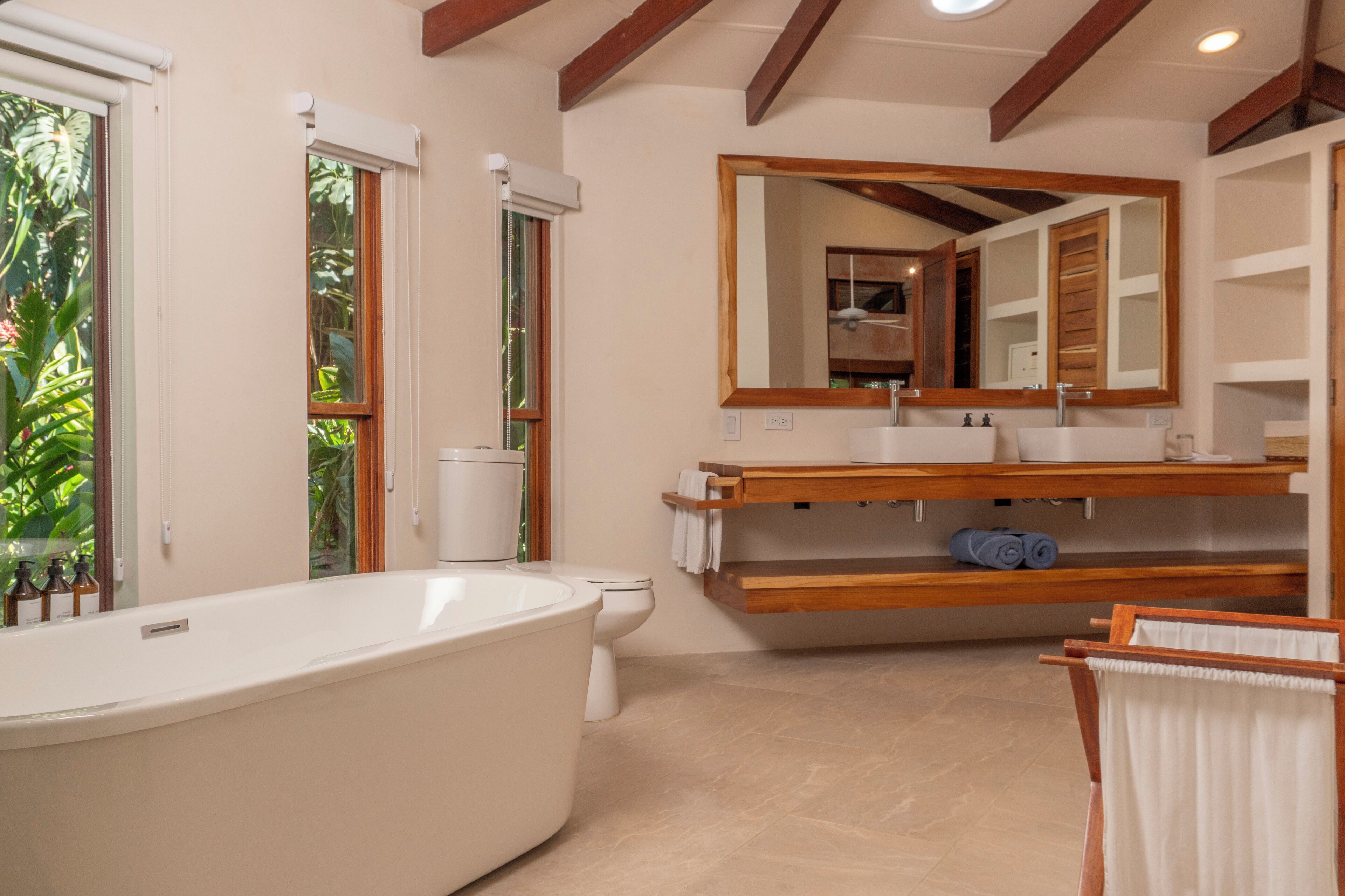A modern bathroom with a freestanding bathtub, a large mirror, and a wooden vanity.