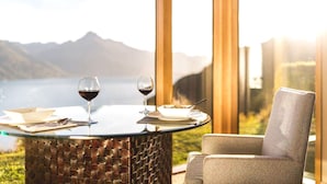 Una mesa de comedor con copas de vino y platos, frente a una vista panorámica de la montaña.