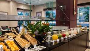 A buffet with various food items and beverages, including bread, fruits, and juices.