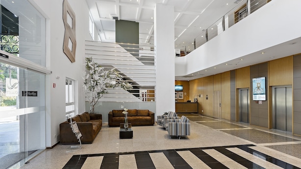 A spacious lobby with a central staircase, seating areas, and a reception desk.