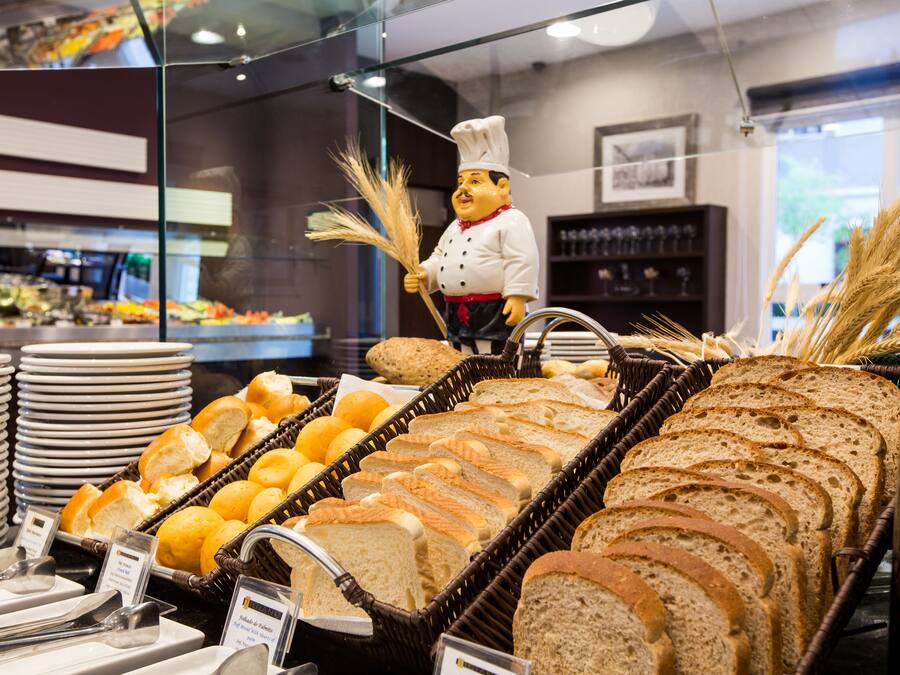 A bakery display with various breads and pastries, a chef figurine, and a glass display case.