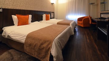 A hotel room with two beds, a desk, and a chair.