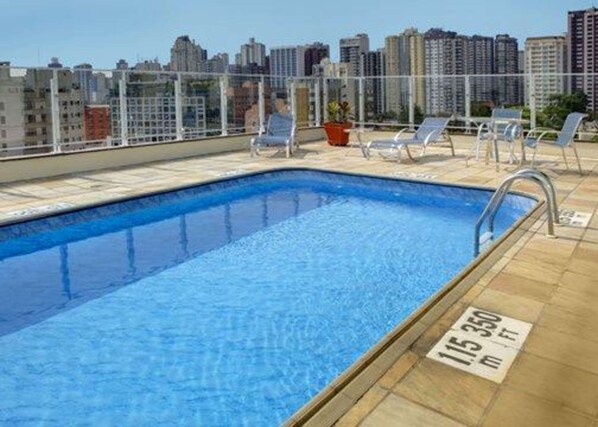 A rooftop pool with clear blue water, surrounded by lounge chairs and a cityscape view. - Quality Hotel Curitiba (Curitiba)