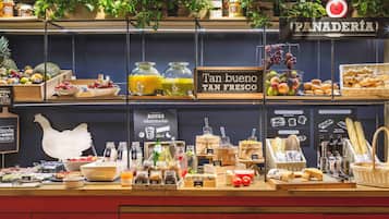 Una barra de desayuno con diversas opciones de comida, como frutas, pasteles y salsas.