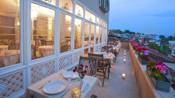An outdoor dining area with tables and chairs, a balcony with potted plants, and a view of the cityscape. - Sumengen Hotel (Istanbul)