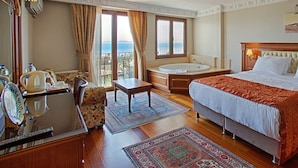 A hotel room with a bed, a desk with a chair, a bathroom with a bathtub, and a view of the sea through the window. - Sumengen Hotel (Istanbul)