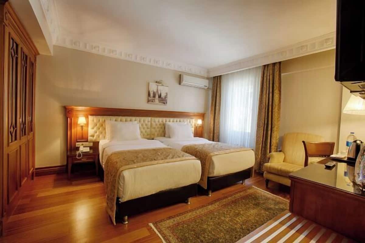 Habitación de hotel con dos camas, televisión, escritorio y silla.