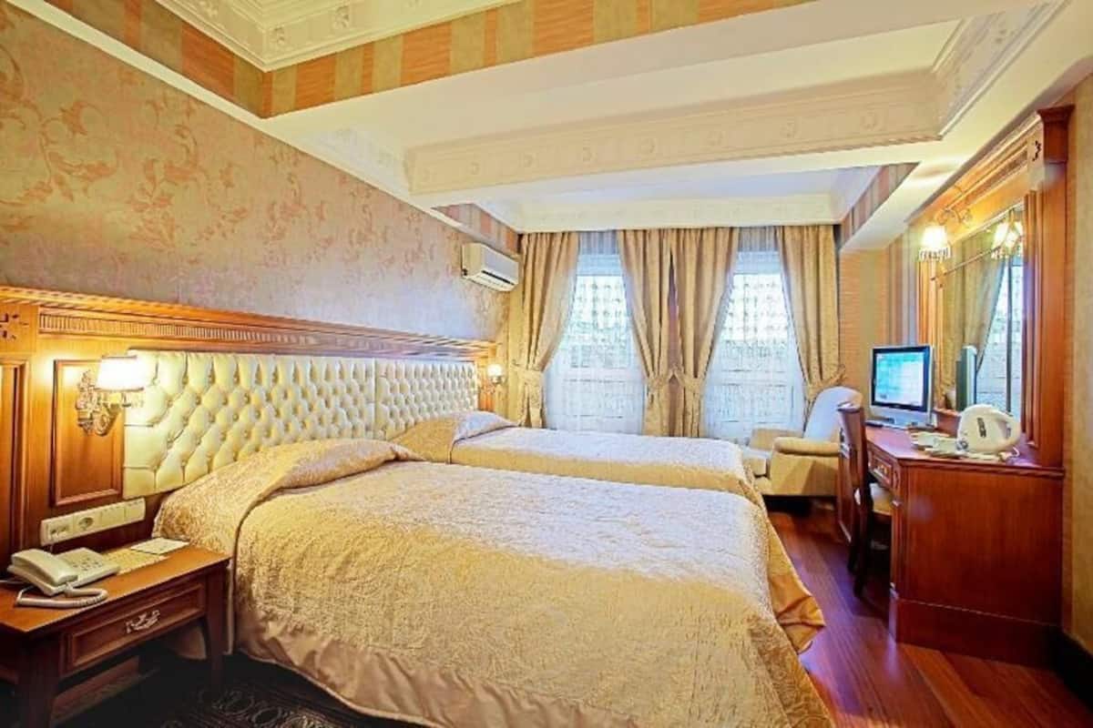 Una habitación de hotel con dos camas, un escritorio, una silla, un teléfono y un televisor.