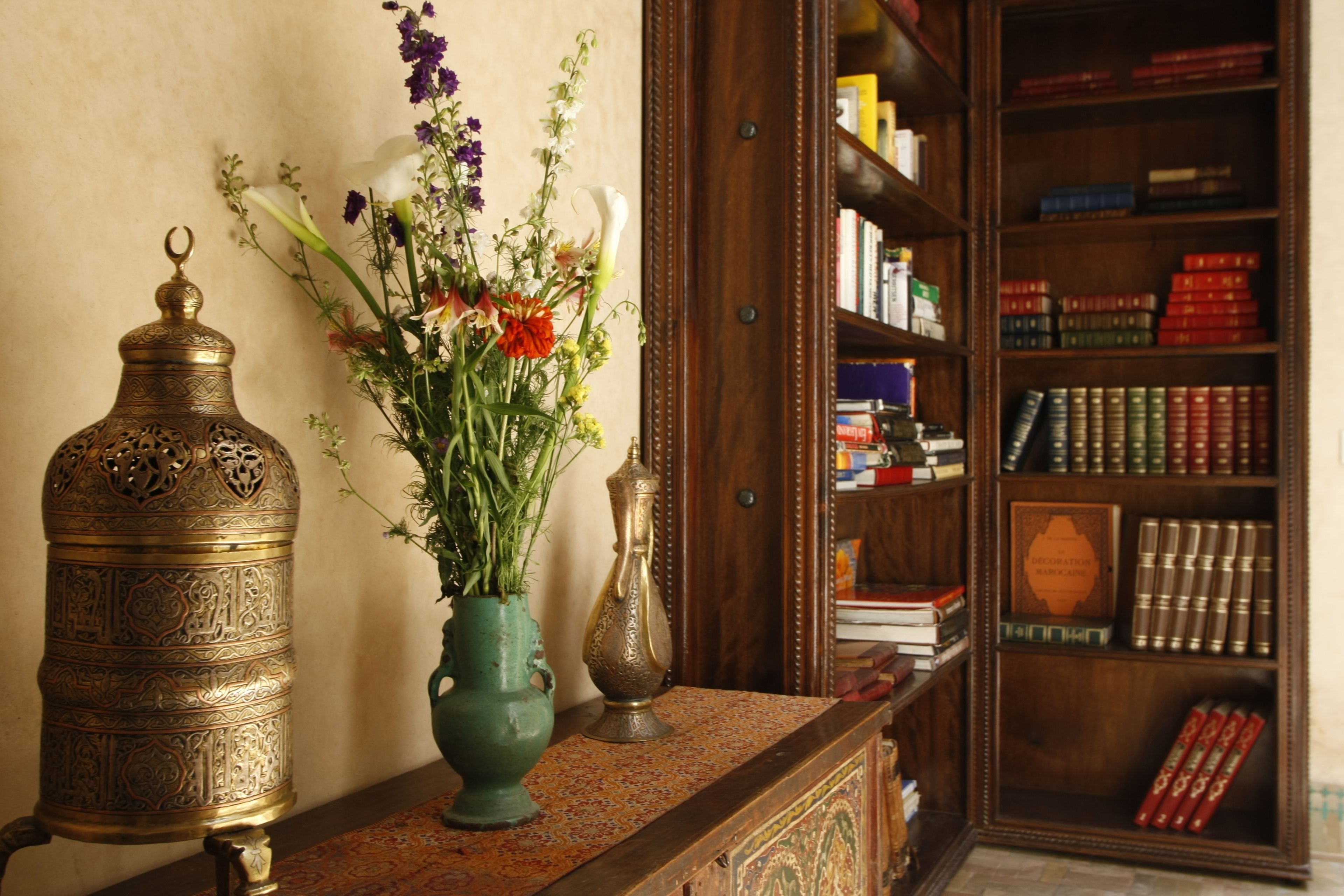 Una estantería de madera llena de libros y un objeto decorativo de bronce.