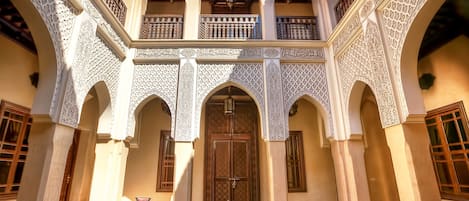 An interior courtyard with arches, a central fountain, and a table with chairs.