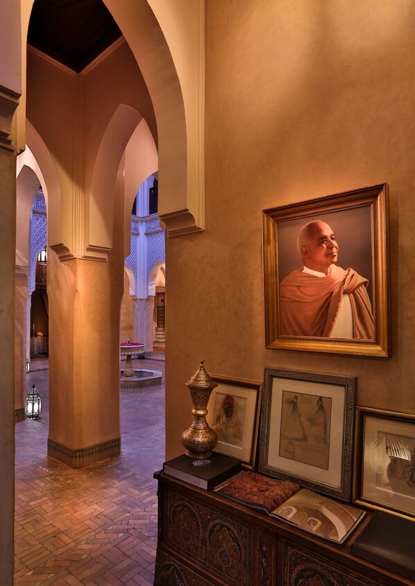 A corridor with arches, a framed portrait, and a decorative lamp.