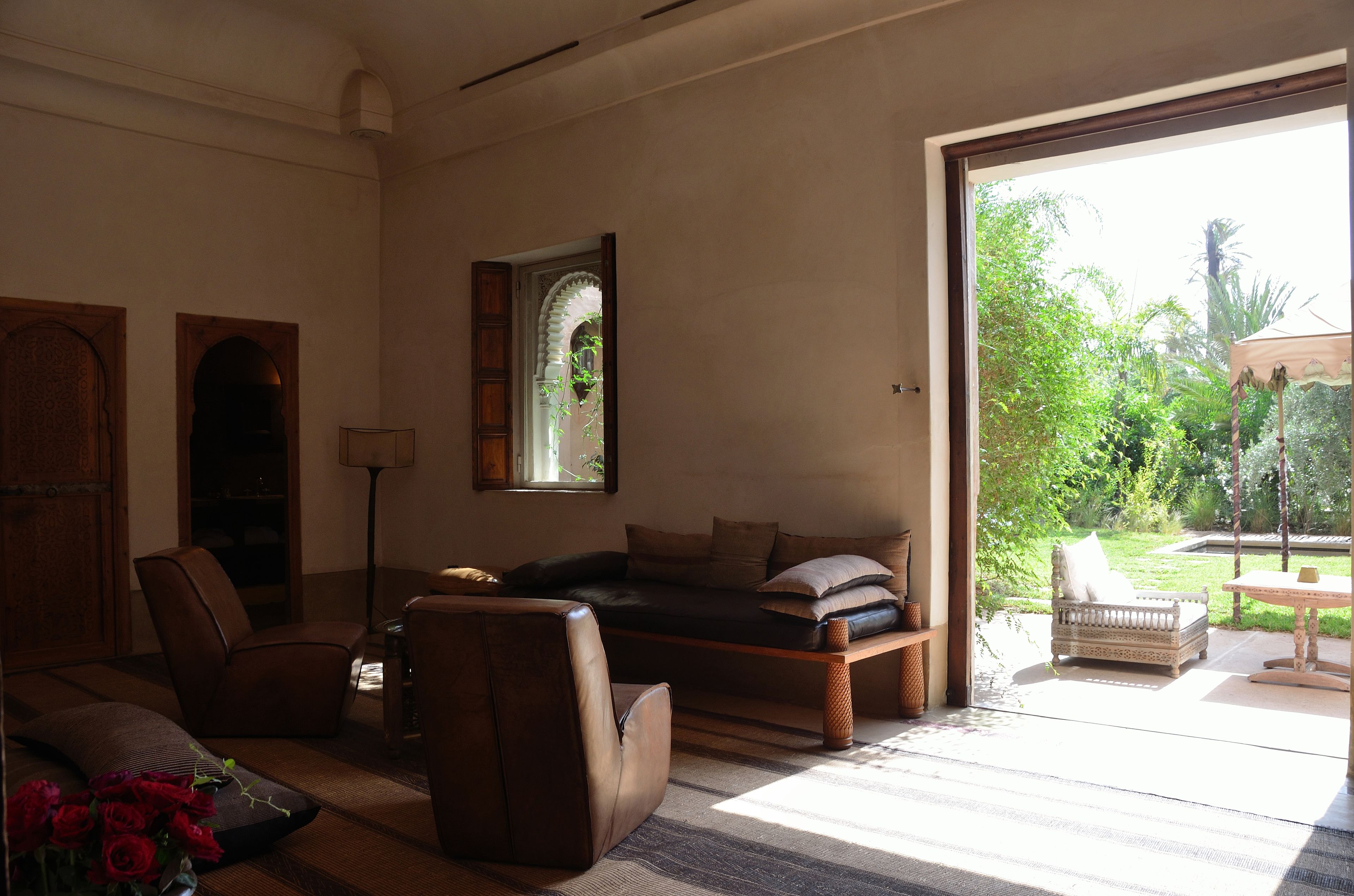 Una sala de estar con sofá, sillas, una mesita de centro y vistas a un jardín a través de un ventanal.