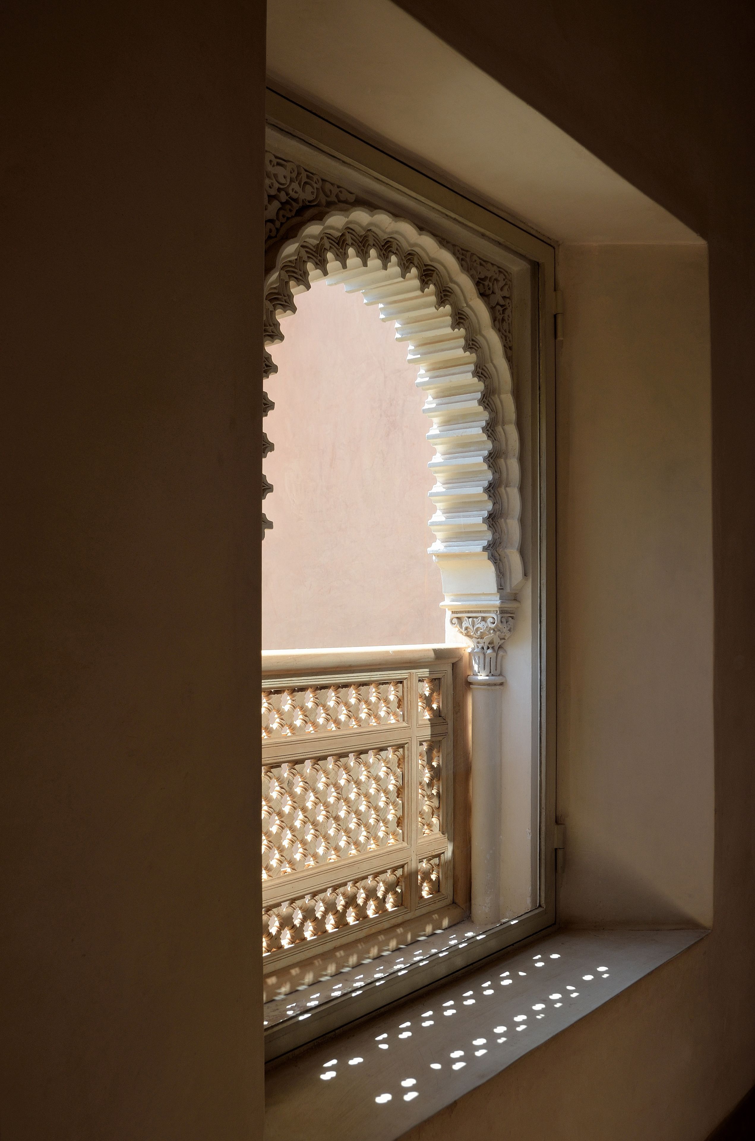 A window with intricate white lattice work and a decorative arch.