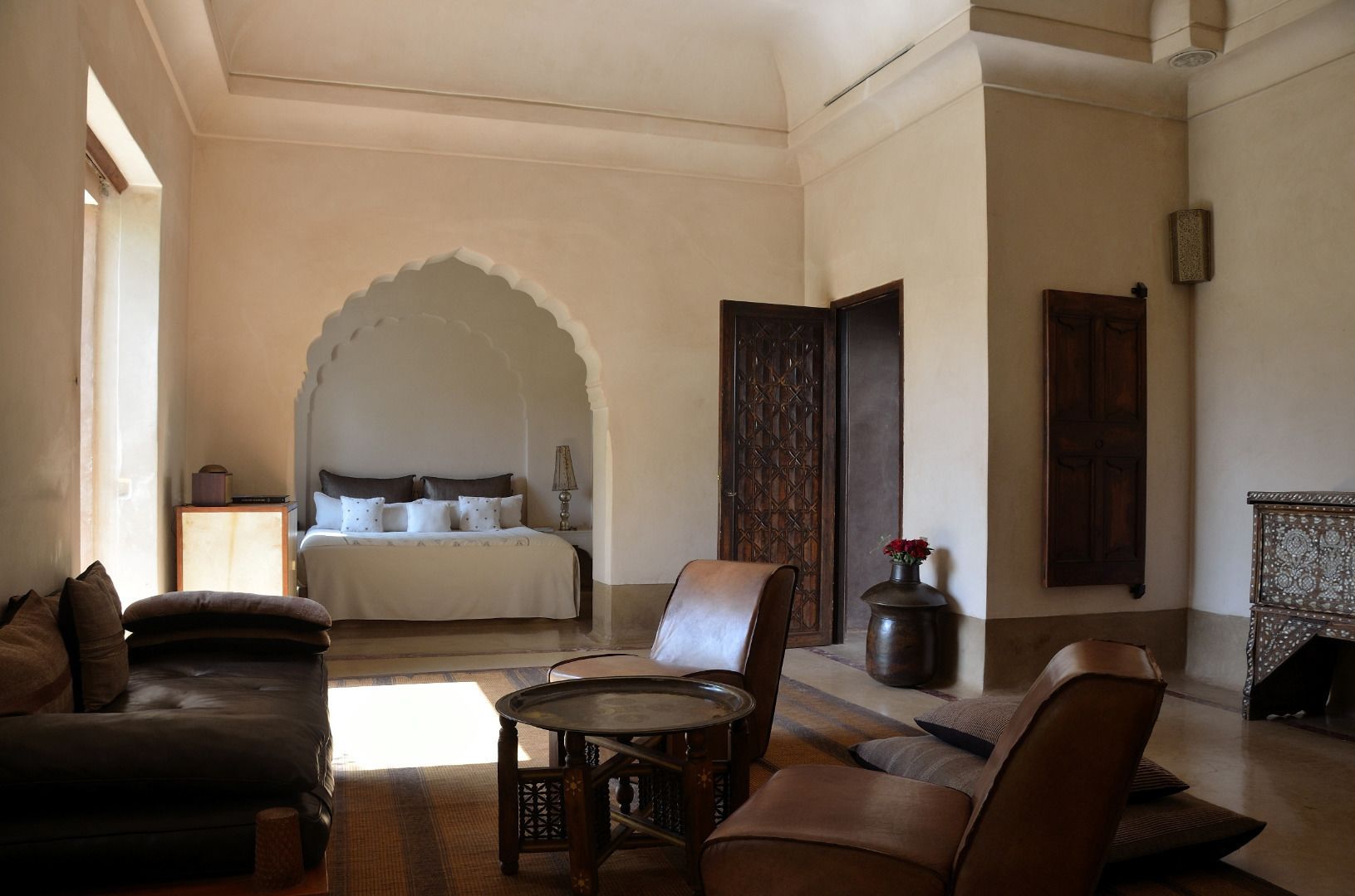 Une pièce spacieuse avec un grand lit, un coin salon doté d’une table ronde et un arc décoratif.