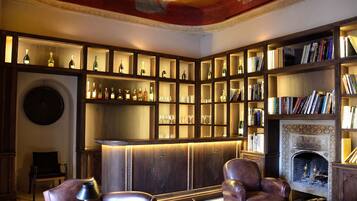 A library with bookshelves, a fireplace, and leather chairs.
