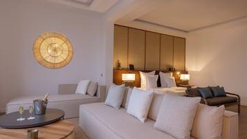 Une chambre d’hôtel moderne avec un grand canapé, une table basse ronde et une lampe fixée au mur.