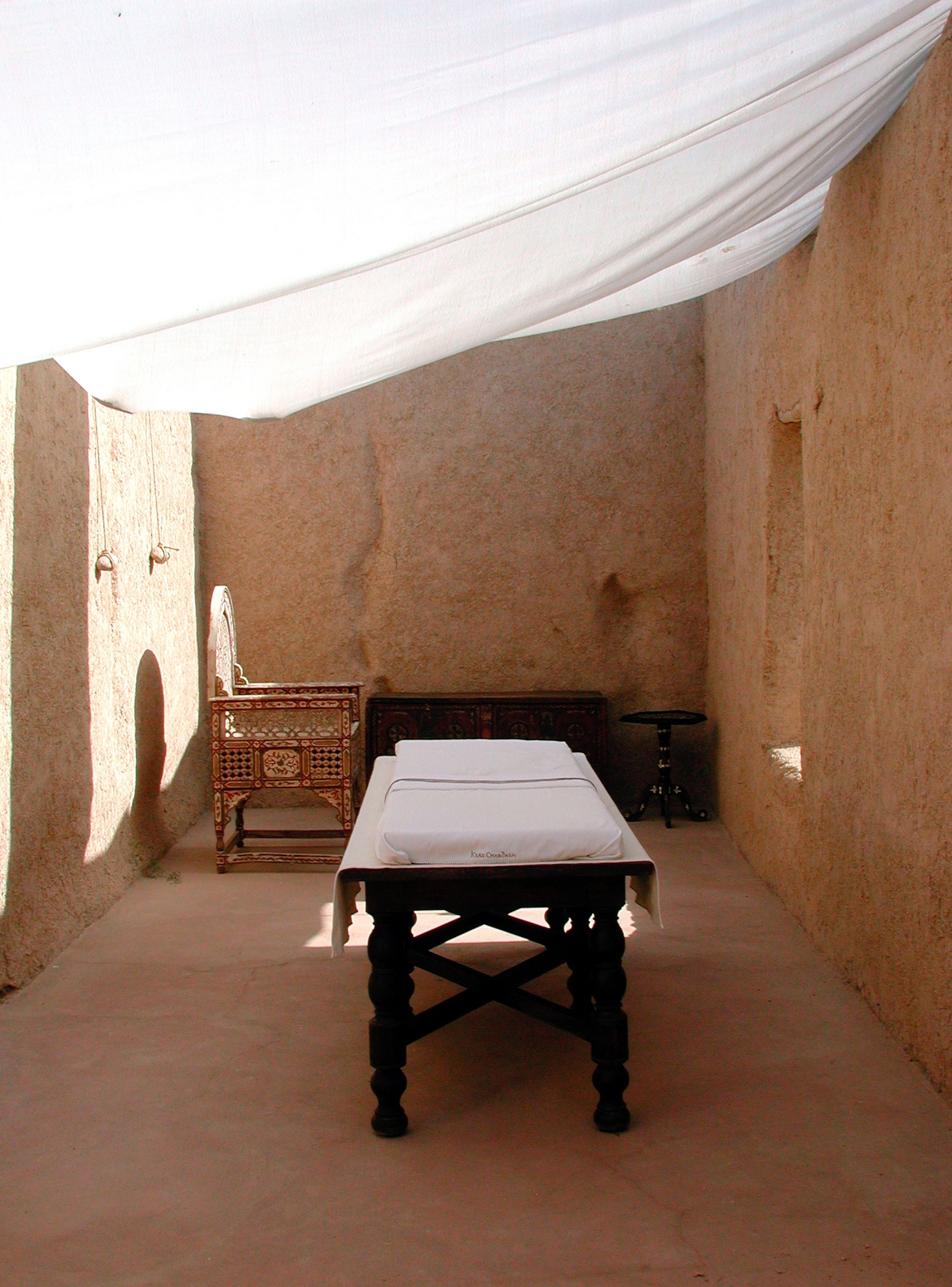 A room with a bed, a small table, and a chair.
