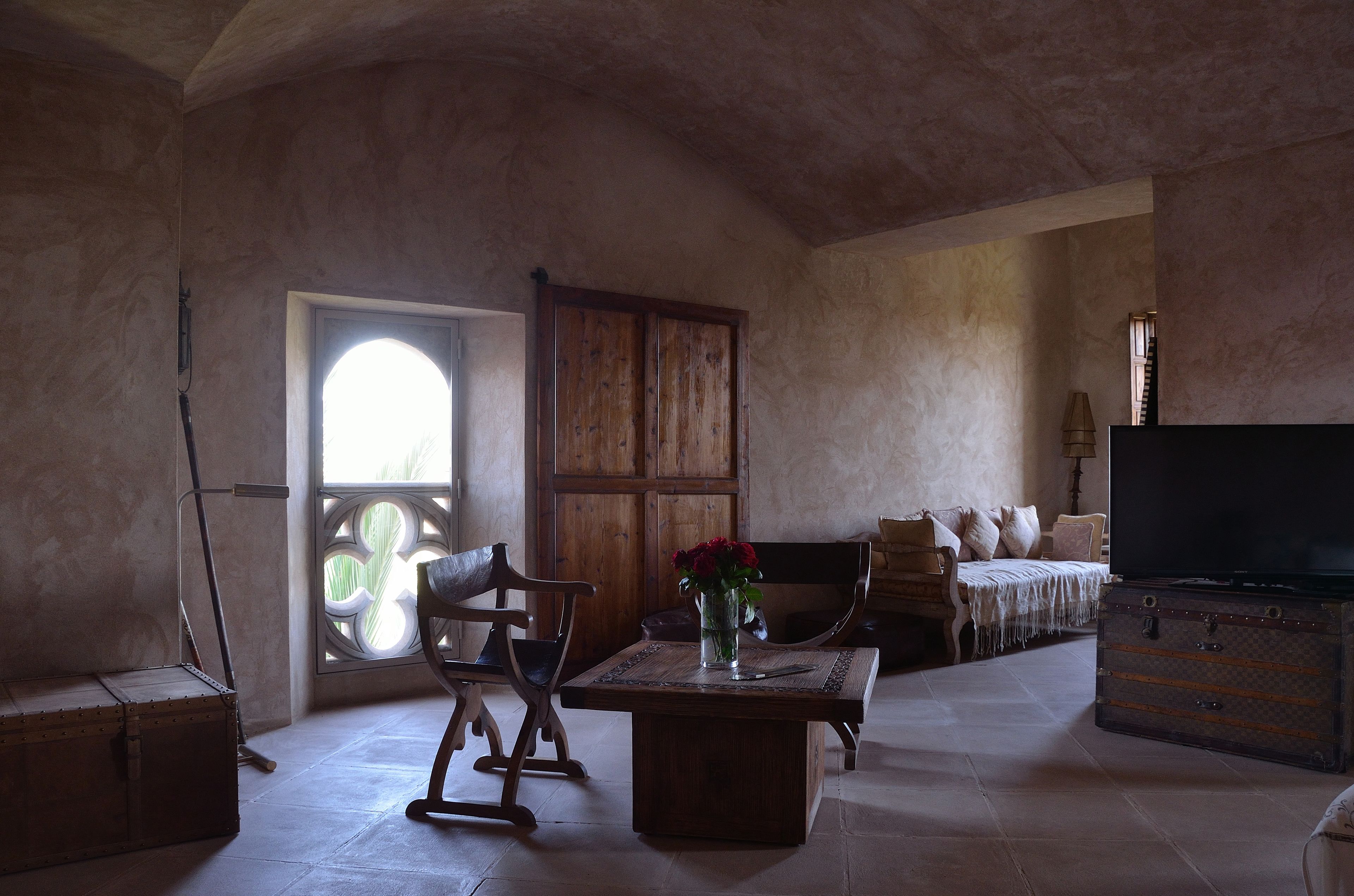 A rustic room with a wooden table, a bench, a television, and a large window.