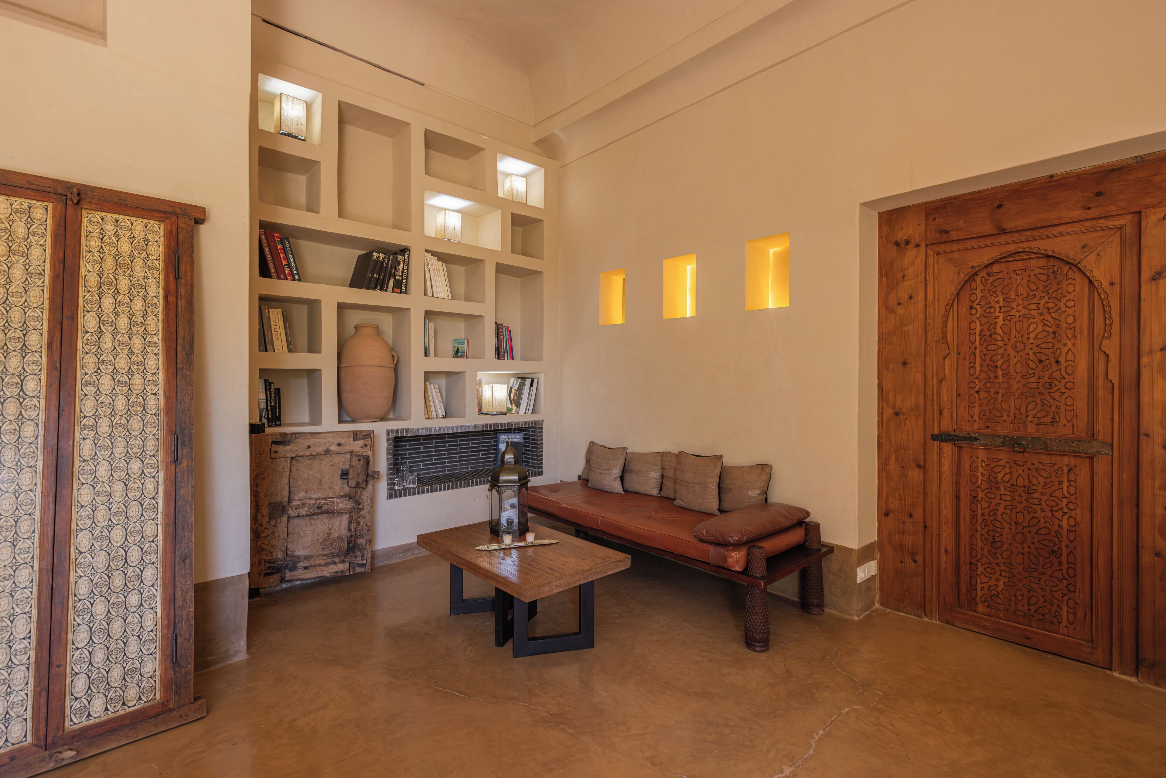 A spacious living area with a wooden sofa, a coffee table, and a bookshelf.