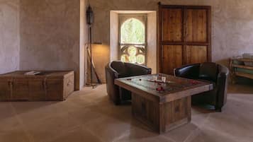 A room with a wooden table, two leather chairs, a wooden cabinet, and a large window with a view of trees.