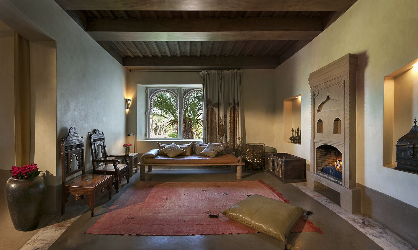 A cozy living room with a fireplace, a bench, and a large window with curtains.