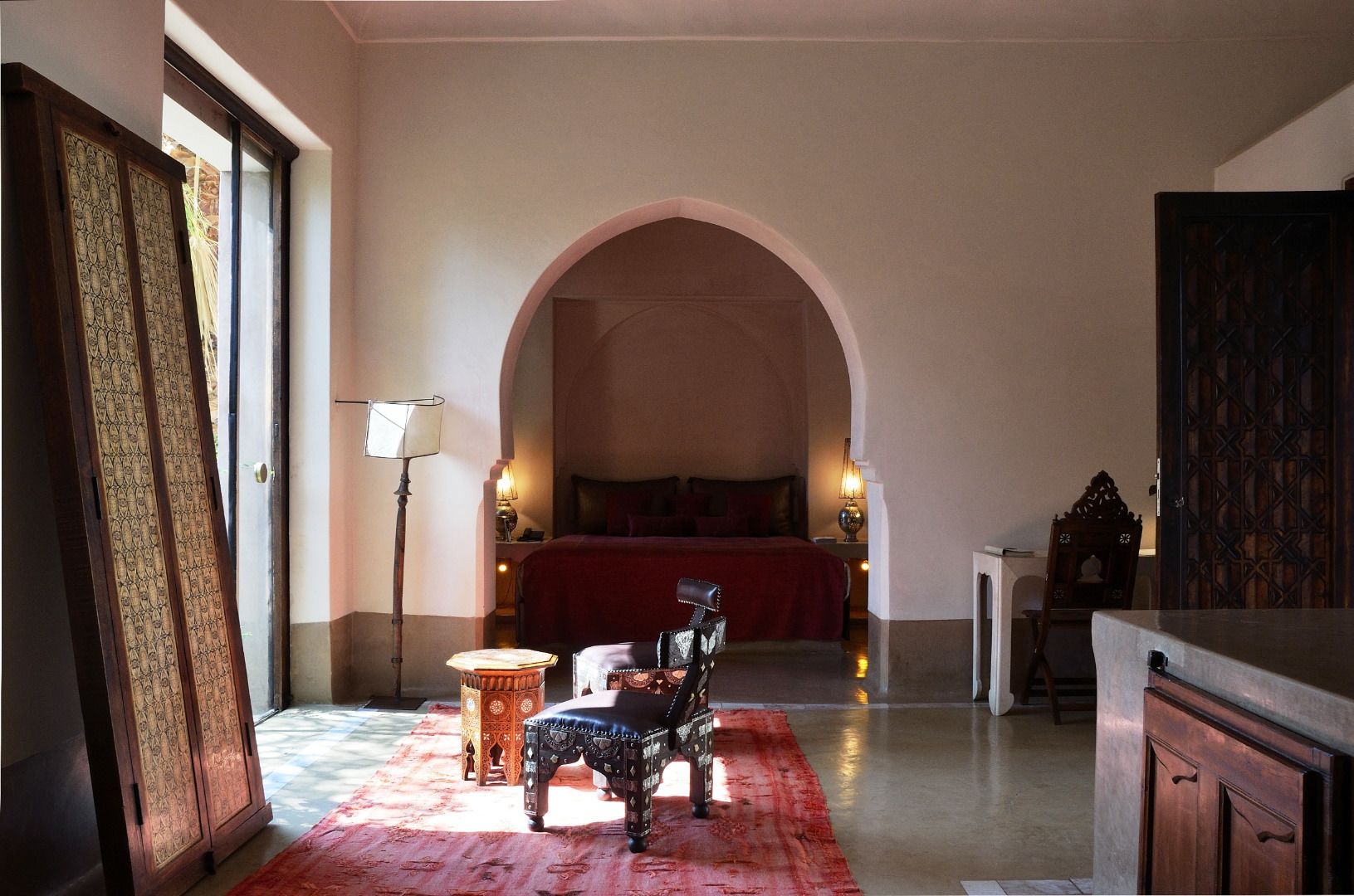 Une chambre à coucher avec un grand lit, une petite table, une chaise et un placard.