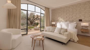 A modern hotel room with a large window, a sofa, a chair, and a small table with books.