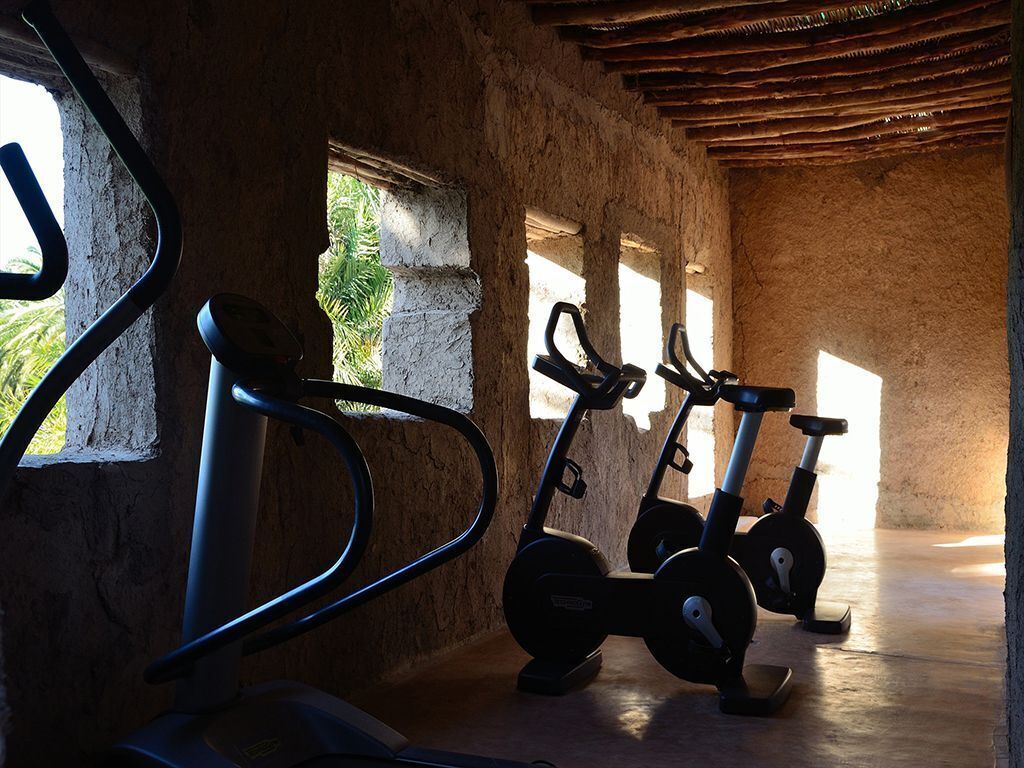 A gym with exercise bikes and a stationary bike, with natural light coming through windows.
