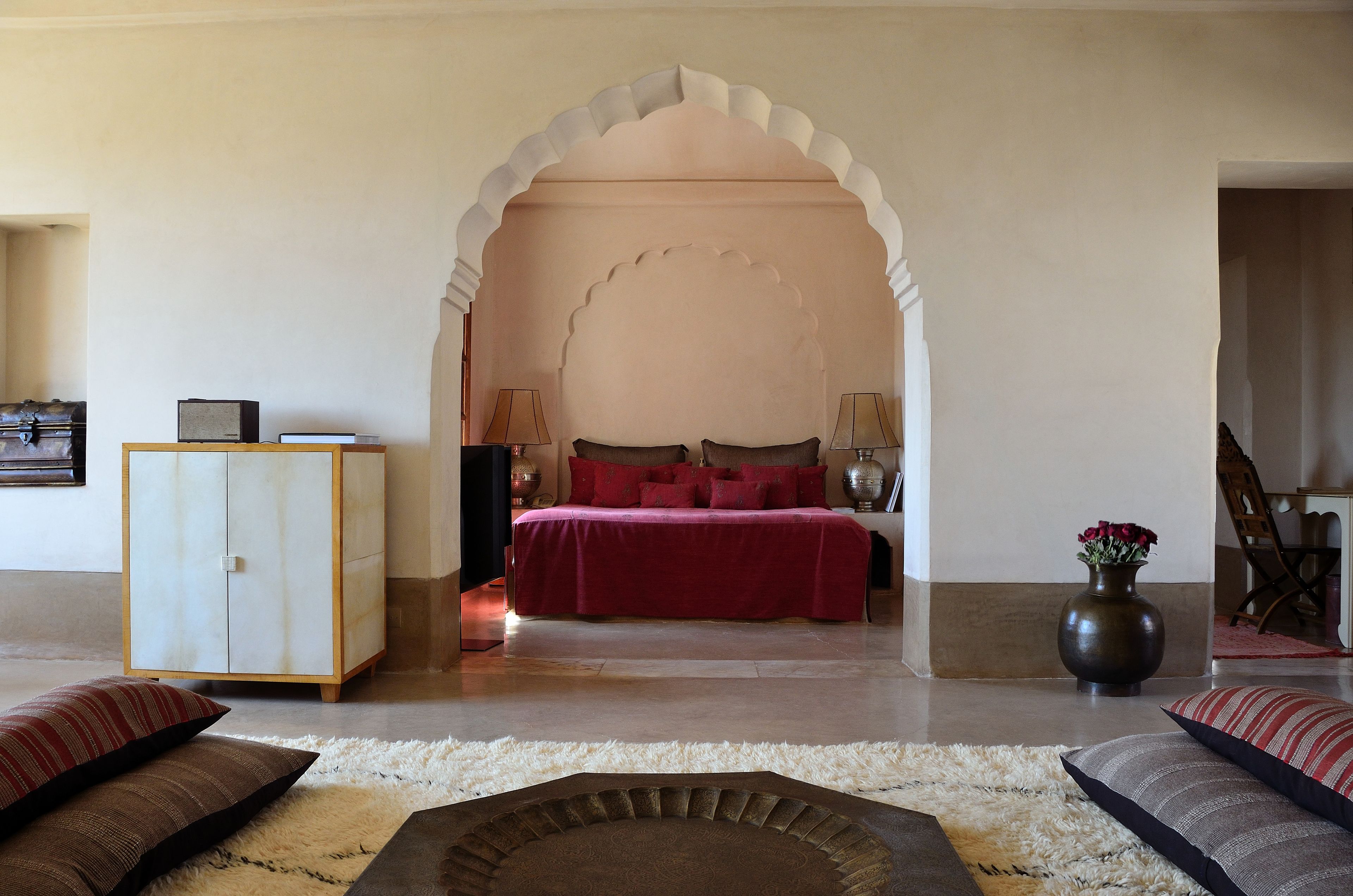 Een slaapkamer met een bed, een kast en een decoratieve boog.