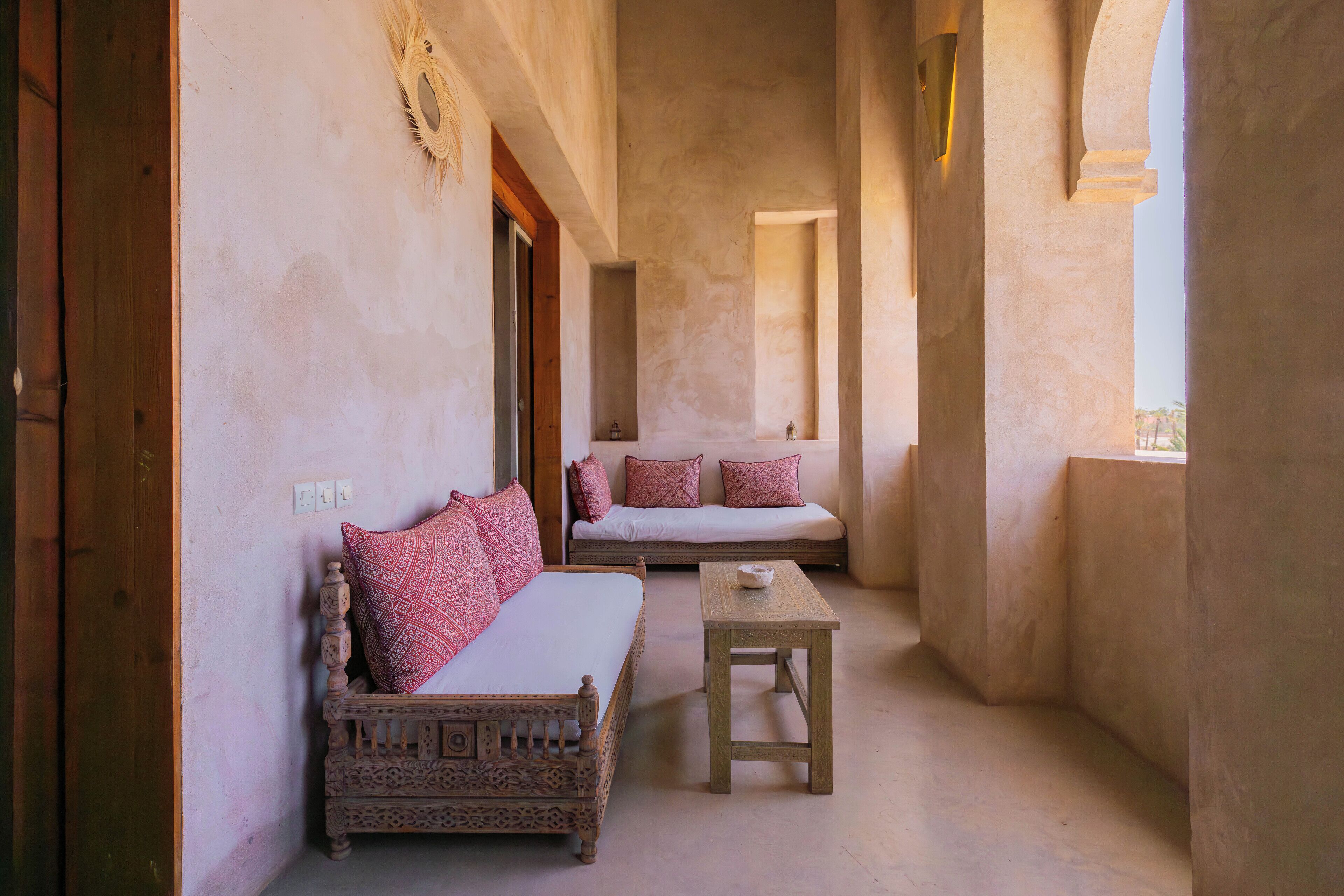 A narrow room with a bed, a small table, and a bench.
