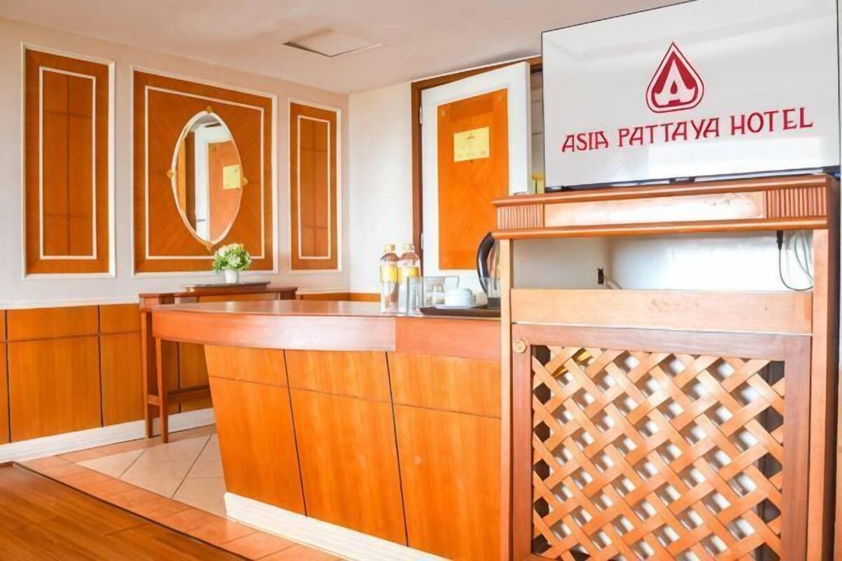 A reception area with a wooden counter, a mirror, and a sign for Asia Pattaya Hotel.