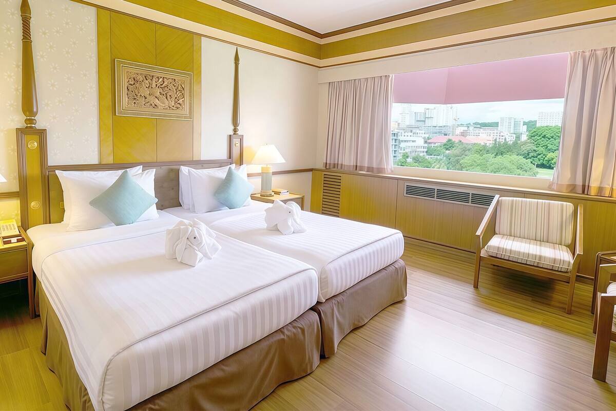 A hotel room with two beds, bedside lamps, a chair, a window with a view, and a decorative wall piece.