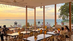 An outdoor dining area with tables and chairs, large windows, and ceiling fans. - Asia Pattaya Hotel (Pattaya)
