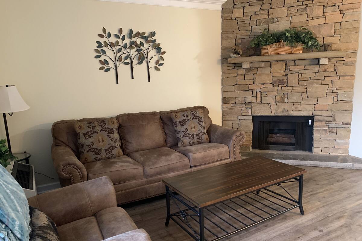 A living room with a stone fireplace, a sofa, and a coffee table.