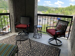 Un balcon avec deux chaises, une petite table et un tapis à motifs.